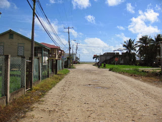 a dirt road with houses and power lines