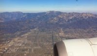 an airplane wing with a city and mountains in the background