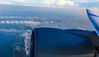 an airplane wing and engine with city and water below