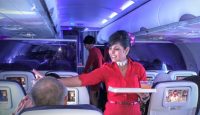 a woman in a red dress holding a tray in an airplane