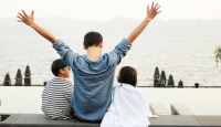 a group of people sitting on a ledge with their arms raised