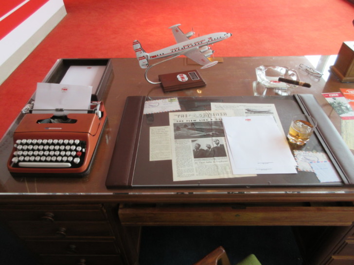 a desk with a typewriter and a model airplane on it