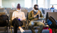 a man and woman sitting in chairs with masks on their faces