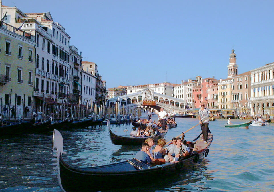 a group of people in a gondola on a canal with Grand Canal in the background