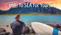 a man sitting on rocks with a surfboard in front of water