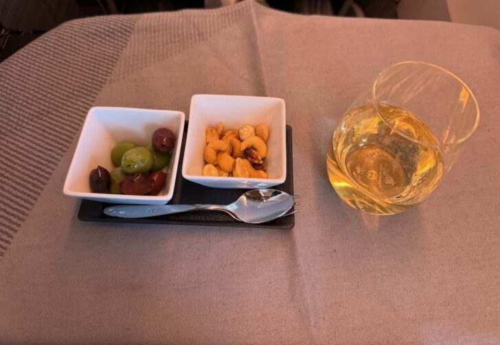 a bowl of nuts and a glass of wine