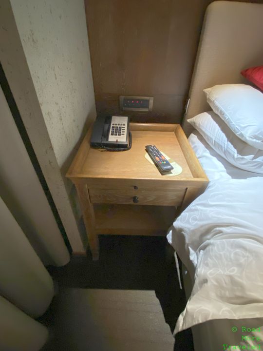 a phone on a table next to a bed