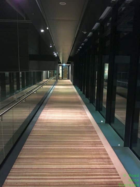 a hallway with glass walls and a striped carpet