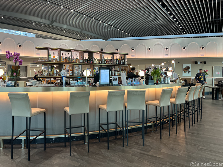 a bar with a row of chairs and a man behind it