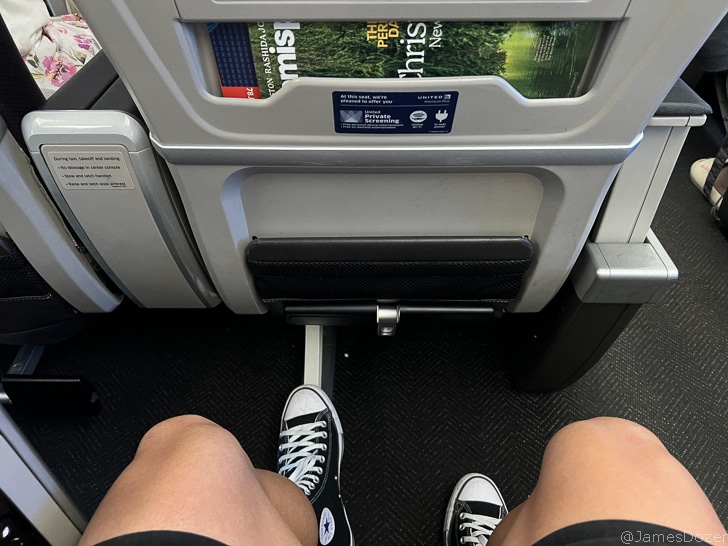 a person's legs in black shoes on an airplane