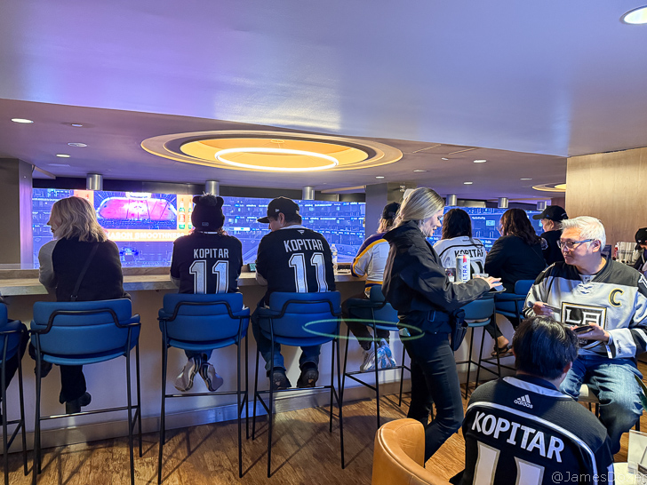 a group of people sitting in chairs in a room with a large screen