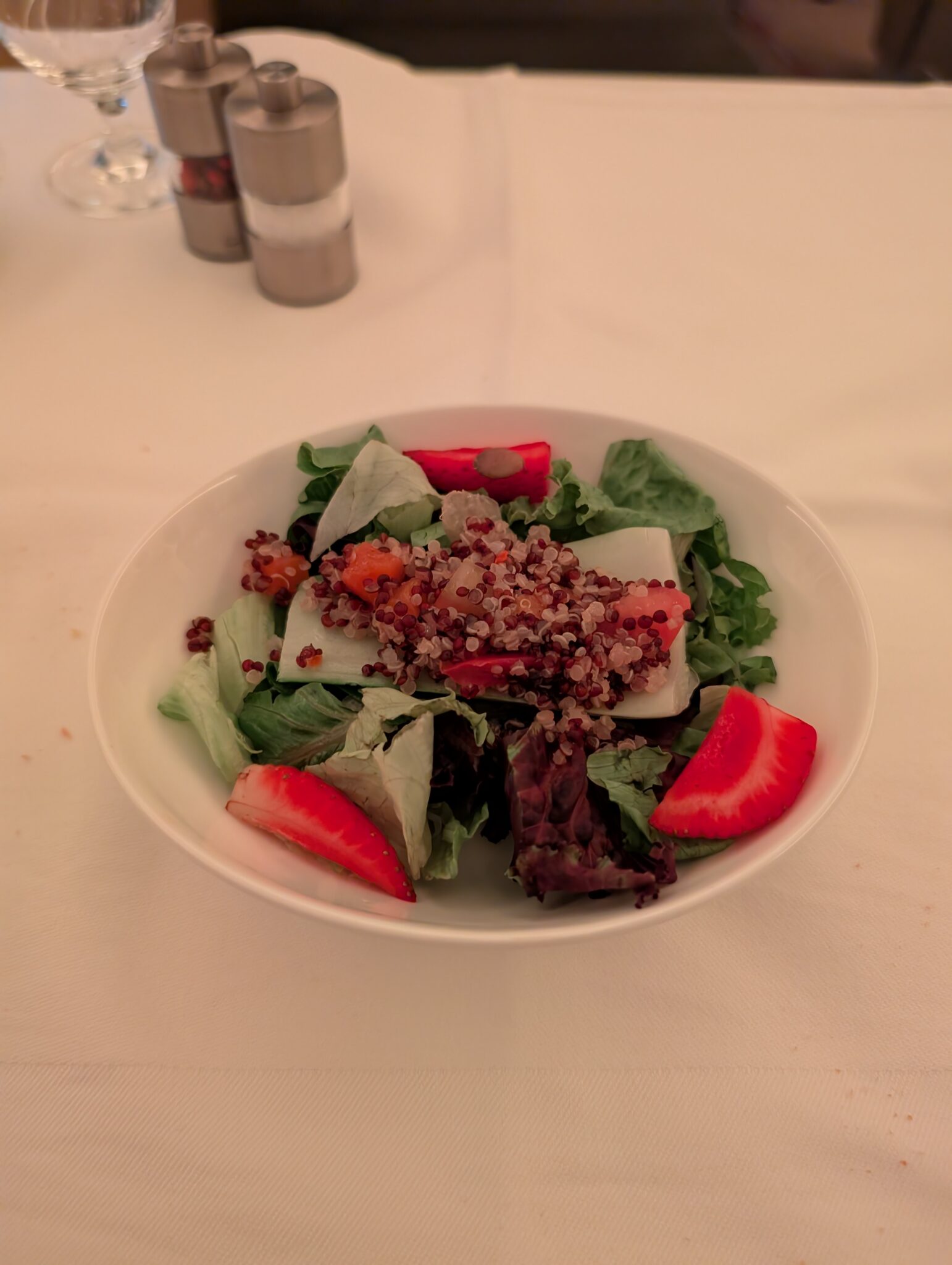 a bowl of salad with strawberries and lettuce