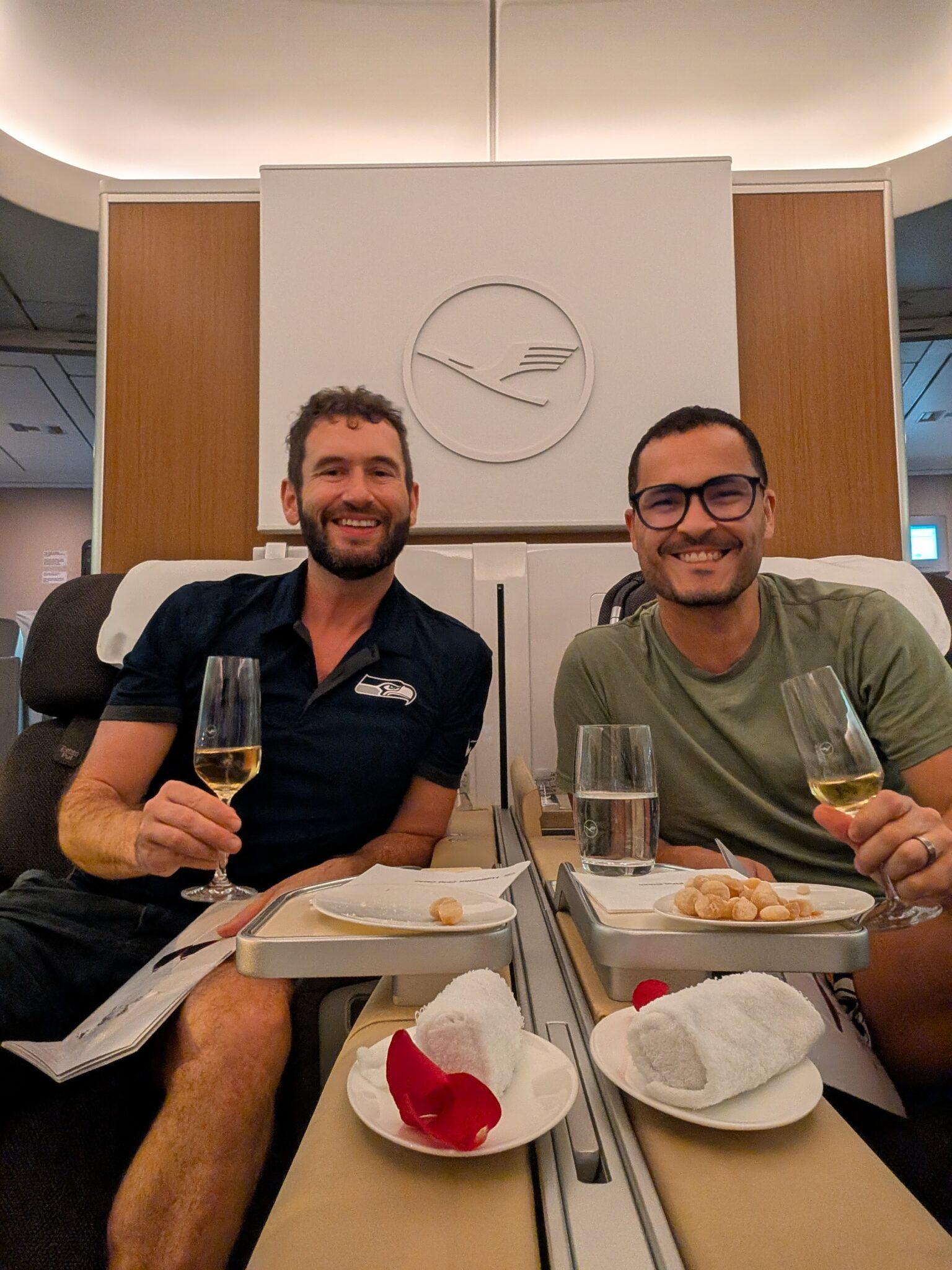 two men sitting in chairs holding drinks and smiling